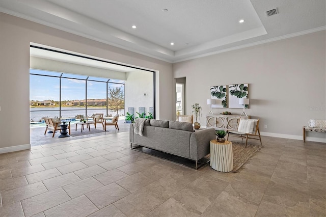 living room with a water view, crown molding, and a tray ceiling