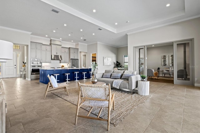 living room with a tray ceiling and ornamental molding