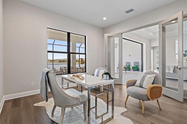 dining area featuring french doors, a water view, and hardwood / wood-style flooring