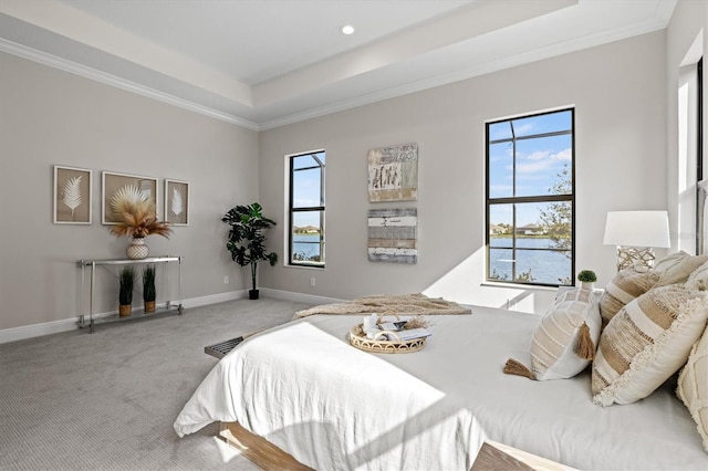 carpeted bedroom featuring a tray ceiling, crown molding, and a water view