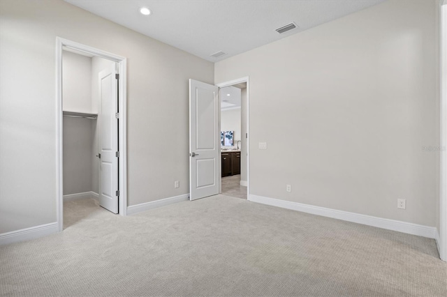 unfurnished bedroom featuring a walk in closet, light carpet, and a closet