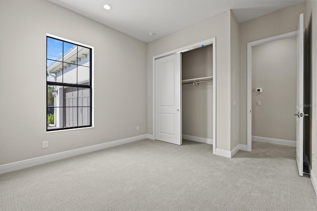 unfurnished bedroom with light carpet and a closet