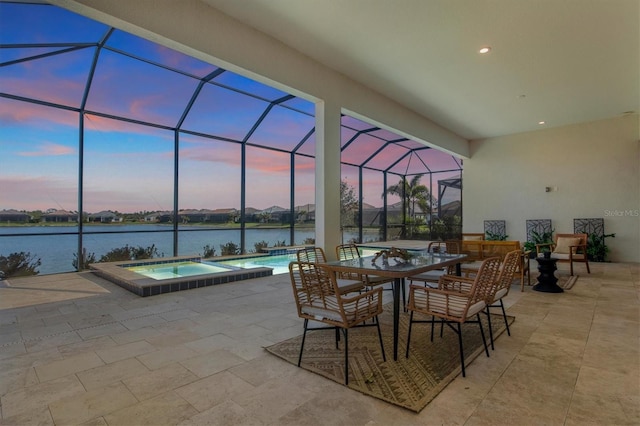 patio terrace at dusk with a water view, a lanai, and a pool with hot tub