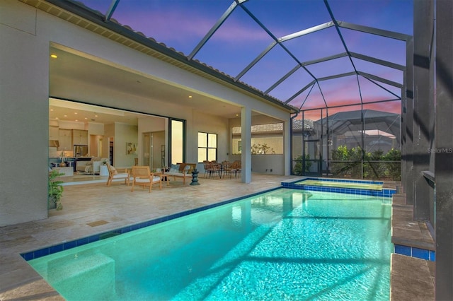 pool at dusk with a patio area, a lanai, and an in ground hot tub