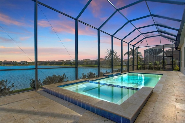 pool at dusk featuring a lanai, a patio area, a water view, and an in ground hot tub