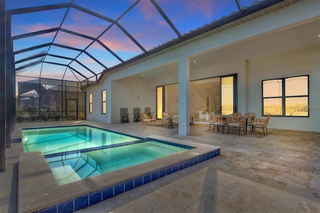 pool at dusk with an in ground hot tub, a patio, and a lanai