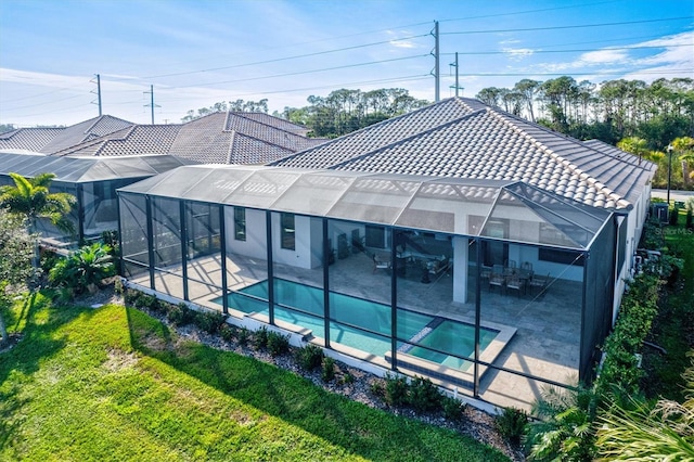 rear view of house with a lanai, a patio area, outdoor lounge area, and a lawn