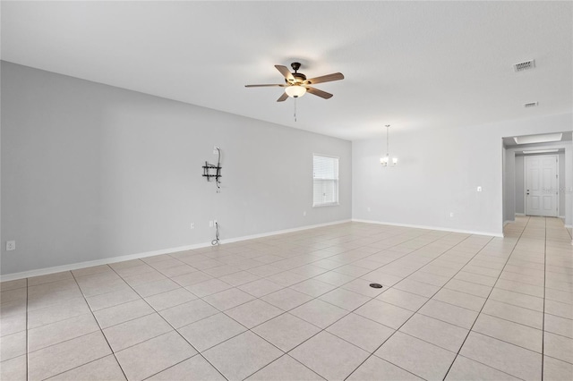 tiled spare room featuring ceiling fan with notable chandelier