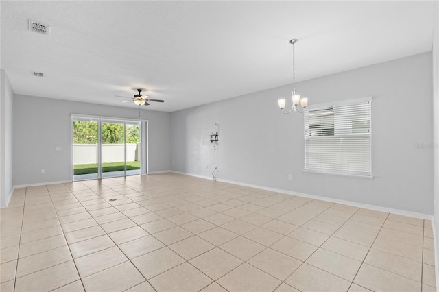 empty room with ceiling fan with notable chandelier and light tile patterned floors