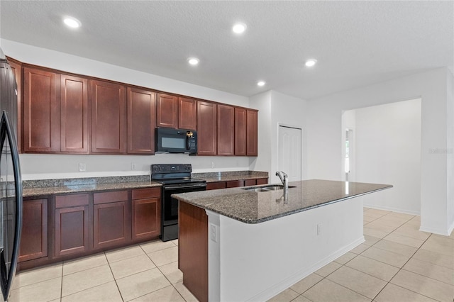 kitchen with black appliances, sink, dark stone countertops, an island with sink, and a textured ceiling