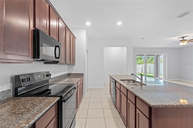 kitchen featuring a kitchen island with sink, black appliances, sink, dark stone countertops, and light tile patterned flooring