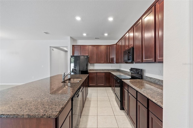 kitchen featuring sink, an island with sink, a textured ceiling, light tile patterned flooring, and black appliances