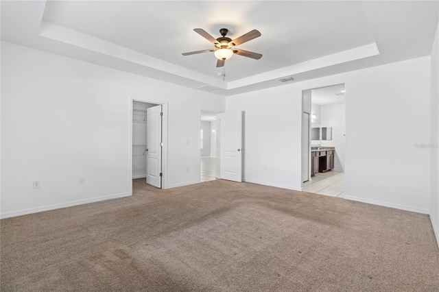 carpeted spare room featuring a tray ceiling and ceiling fan