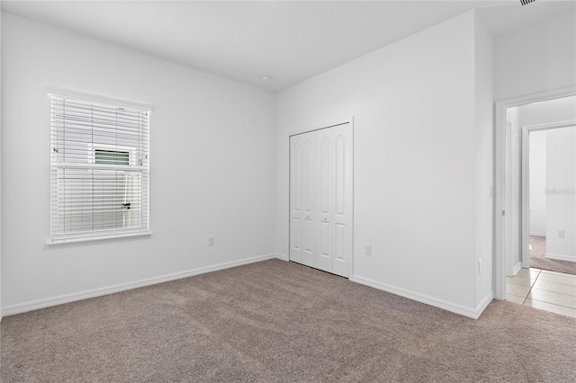 unfurnished bedroom featuring light carpet and a closet