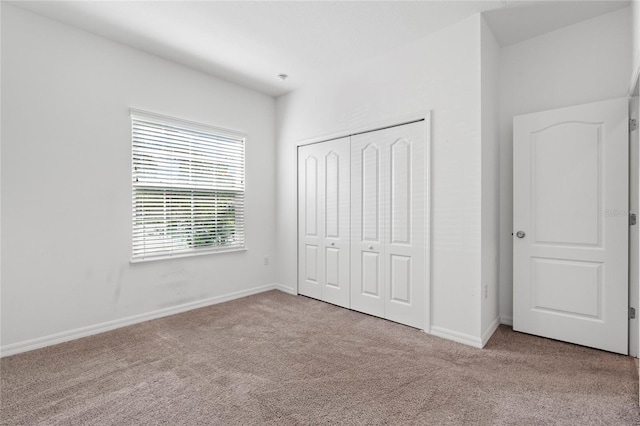 unfurnished bedroom featuring light colored carpet and a closet