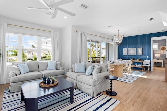 living room featuring ceiling fan with notable chandelier and light hardwood / wood-style floors