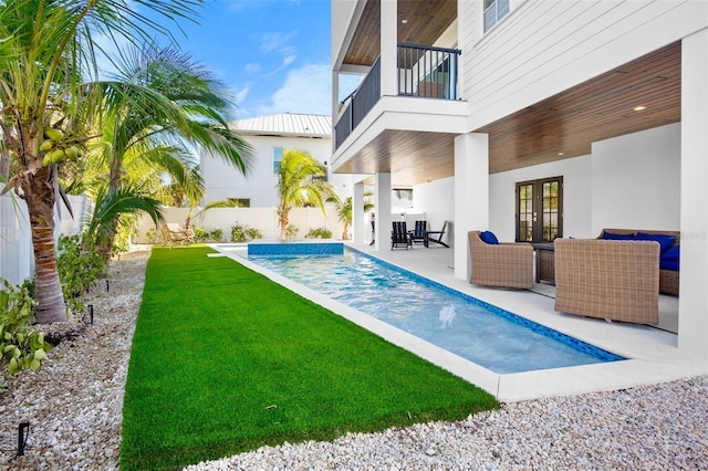 view of swimming pool featuring a lawn, outdoor lounge area, a patio area, and french doors