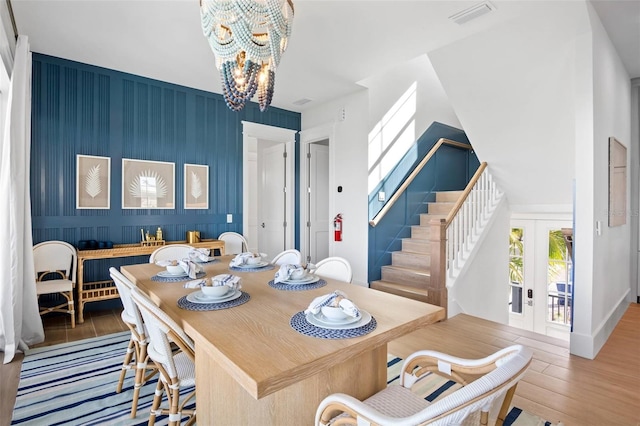 dining space featuring hardwood / wood-style floors, french doors, and an inviting chandelier