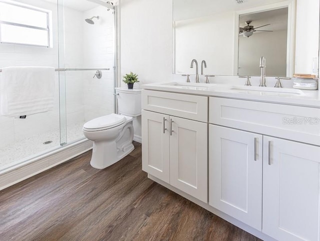 bathroom with walk in shower, vanity, hardwood / wood-style floors, toilet, and ceiling fan