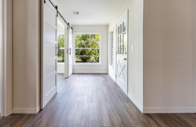 doorway with a barn door and dark hardwood / wood-style floors