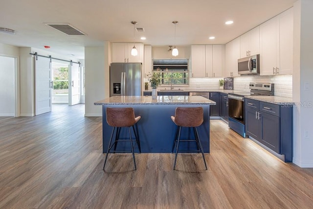 kitchen featuring a barn door, light hardwood / wood-style floors, white cabinets, and stainless steel appliances