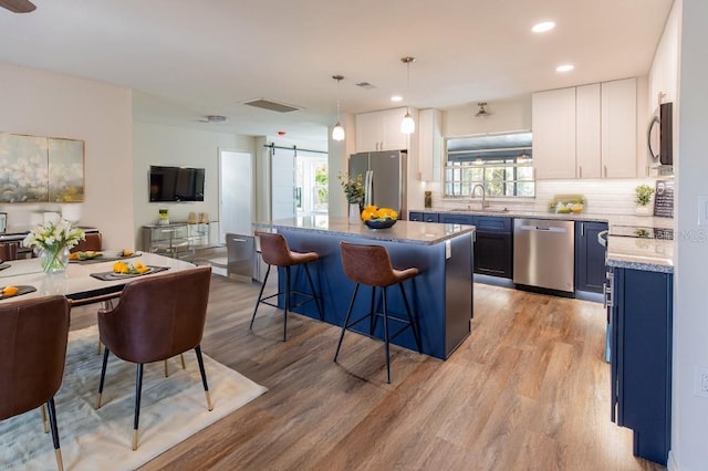 kitchen featuring white cabinetry, appliances with stainless steel finishes, a barn door, and blue cabinetry