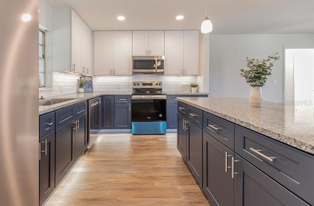 kitchen featuring white cabinetry, light stone counters, appliances with stainless steel finishes, and light hardwood / wood-style flooring