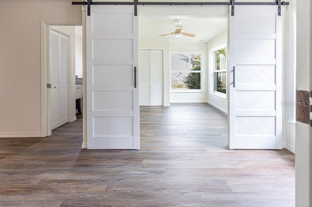 unfurnished room with hardwood / wood-style floors, a barn door, and ceiling fan