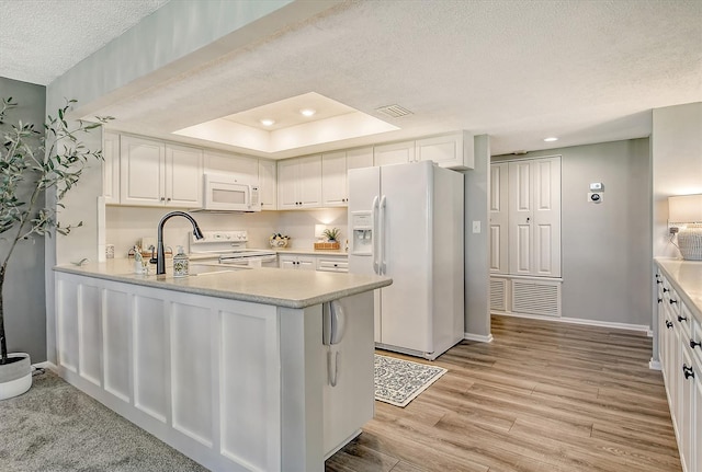 kitchen with white appliances, light hardwood / wood-style flooring, a textured ceiling, white cabinetry, and kitchen peninsula