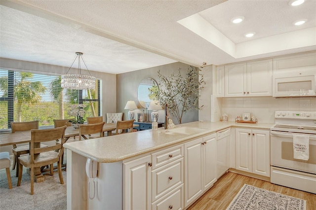 kitchen featuring kitchen peninsula, light hardwood / wood-style flooring, hanging light fixtures, and white appliances