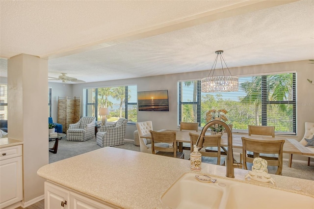 kitchen featuring pendant lighting, a textured ceiling, light colored carpet, and white cabinetry