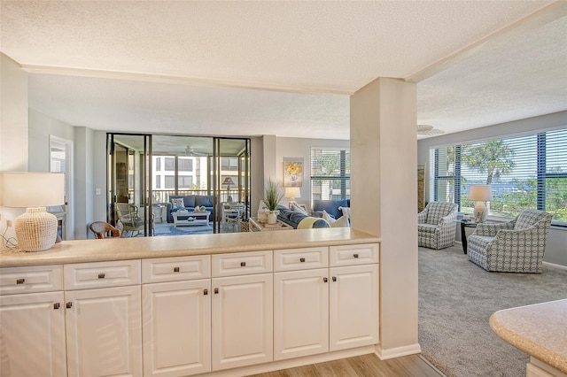 kitchen featuring white cabinets, a textured ceiling, and light hardwood / wood-style flooring