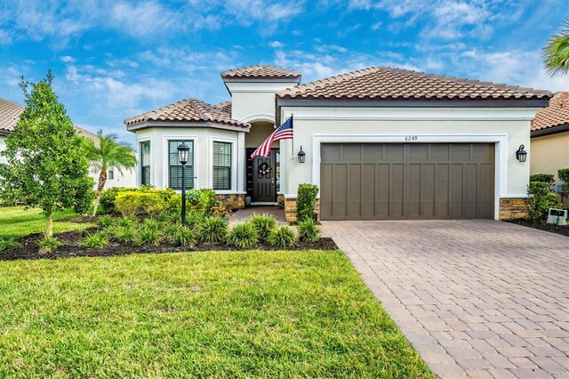 6249 Mesa Gln, Bradenton, FL 34203 - mediterranean / spanish-style house featuring an attached garage, decorative driveway, stone siding, and stucco siding