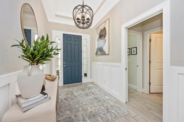 foyer entrance featuring an inviting chandelier, light wood-type flooring, and ornamental molding