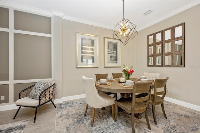 dining room with a notable chandelier, light wood-type flooring, and ornamental molding