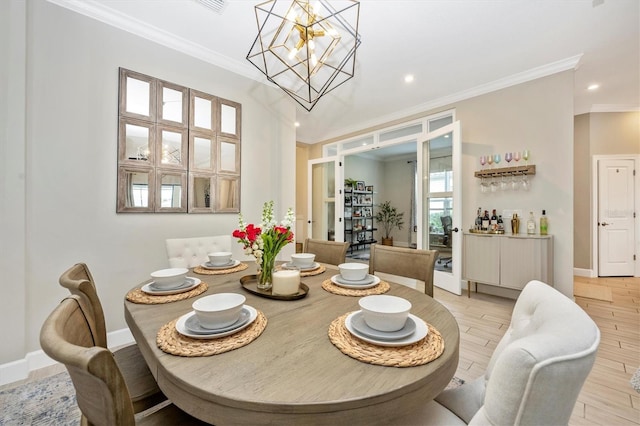 dining room featuring light hardwood / wood-style flooring, crown molding, and a notable chandelier