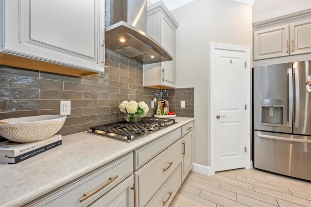 6249 Mesa Gln, Bradenton, FL 34203 - kitchen featuring appliances with stainless steel finishes, wall chimney exhaust hood, backsplash, light wood finished floors, and crown molding