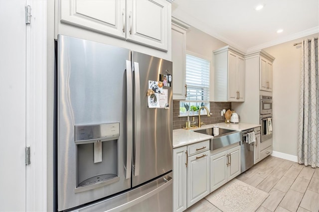 kitchen with white cabinets, decorative backsplash, sink, crown molding, and appliances with stainless steel finishes