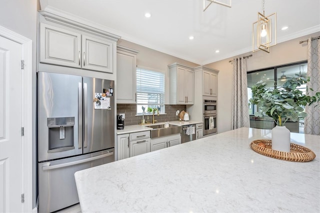 kitchen featuring decorative backsplash, light stone countertops, appliances with stainless steel finishes, and sink