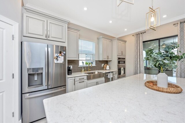 6249 Mesa Gln, Bradenton, FL 34203 - kitchen with stainless steel appliances, a sink, tasteful backsplash, ornamental molding, and light stone countertops