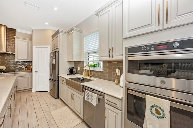 kitchen featuring stainless steel appliances, sink, light stone countertops, wall chimney exhaust hood, and backsplash