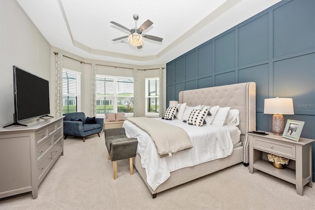 carpeted bedroom featuring a tray ceiling and ceiling fan