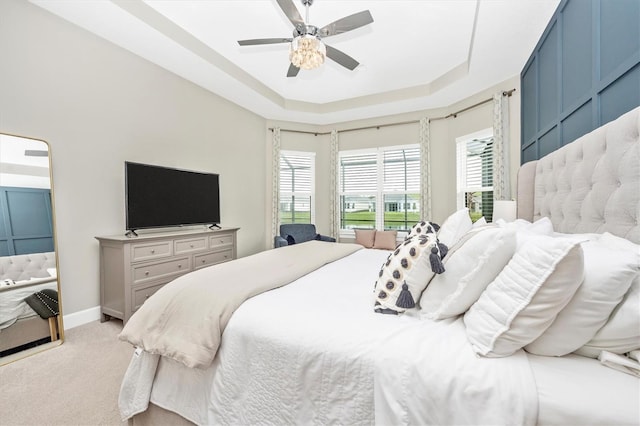 carpeted bedroom with ceiling fan and a tray ceiling