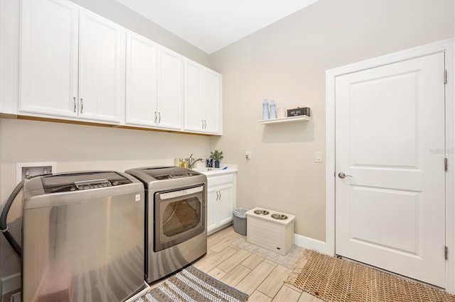 laundry area with light hardwood / wood-style floors, cabinets, sink, and washer and dryer