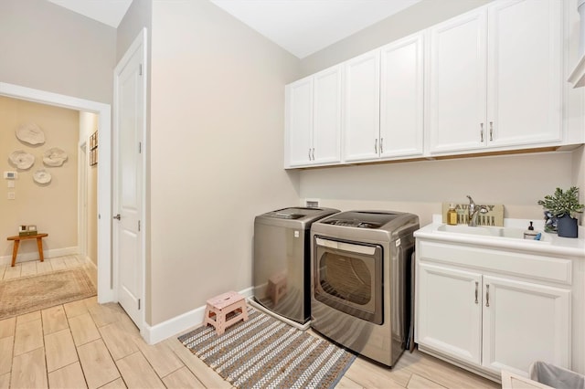 clothes washing area with sink, cabinets, independent washer and dryer, and light hardwood / wood-style floors