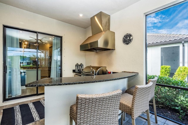 kitchen featuring a kitchen breakfast bar, dark stone countertops, range hood, and kitchen peninsula