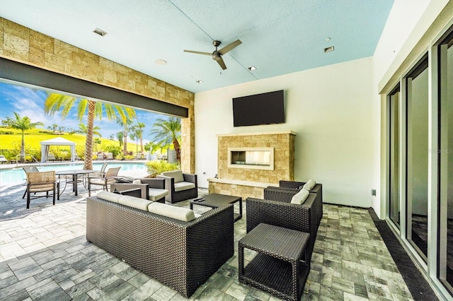 view of patio featuring ceiling fan and an outdoor living space with a fireplace