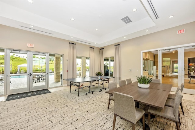 rec room featuring light wood-type flooring, french doors, and a raised ceiling