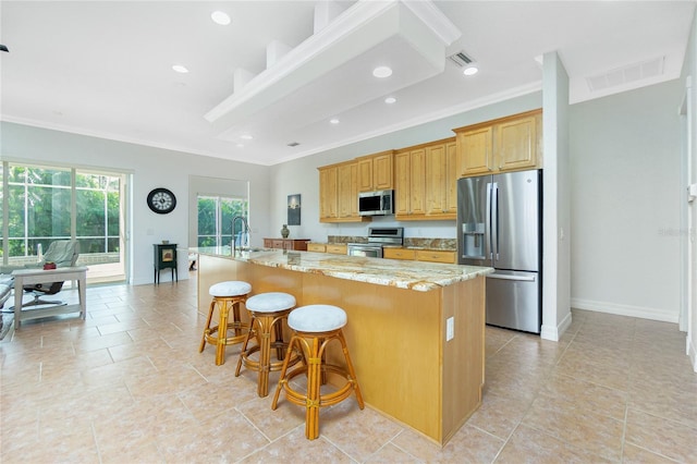 kitchen with a kitchen island with sink, sink, a breakfast bar area, and stainless steel appliances