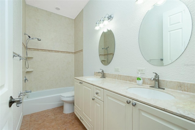 full bathroom featuring tile patterned flooring, tiled shower / bath, vanity, and toilet